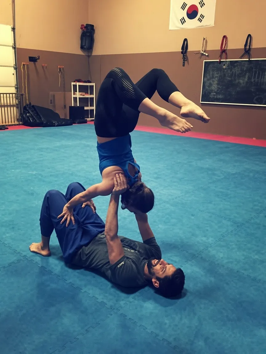 Partners practicing aerial acro yoga on the mats at Bodies in Motion