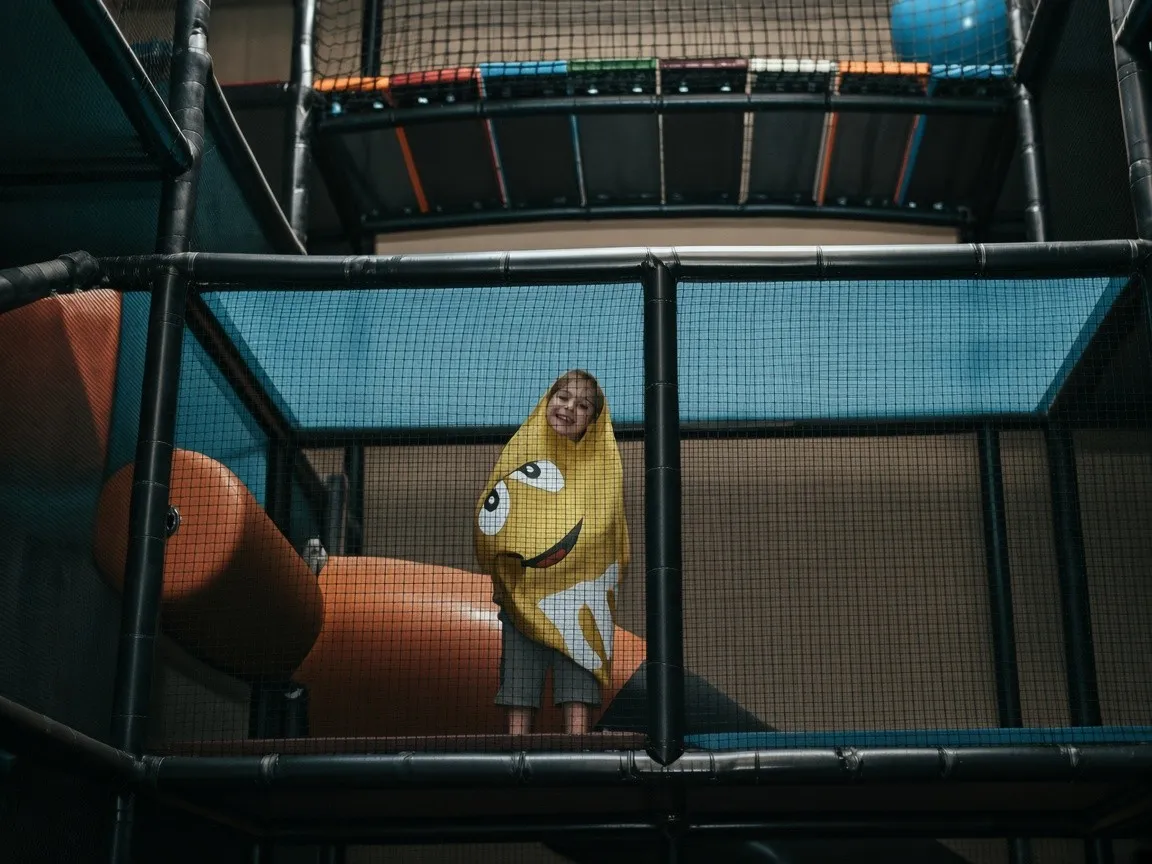 A child wrapped in a yellow costume inside the multi-level soft-play structure