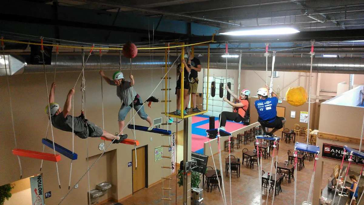 Adults in harnesses and helmets on the indoor high ropes course