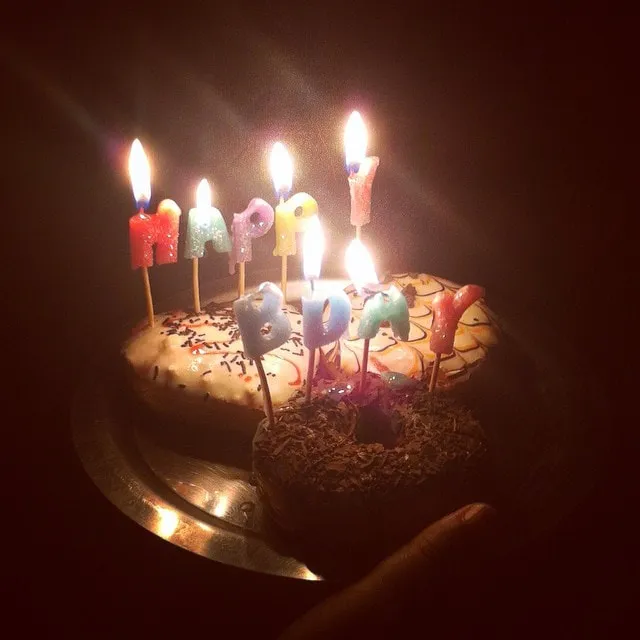 A birthday cake with lit Happy Birthday candles