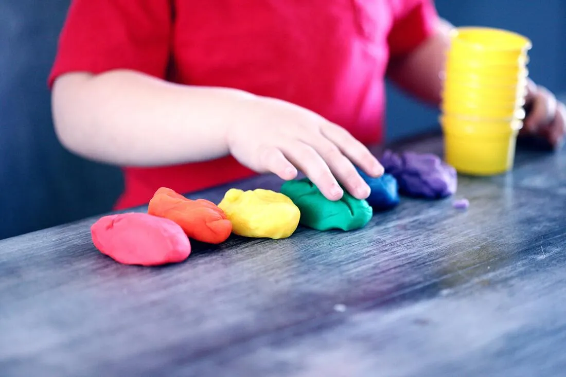 A child pressing colorful modeling clay on a table