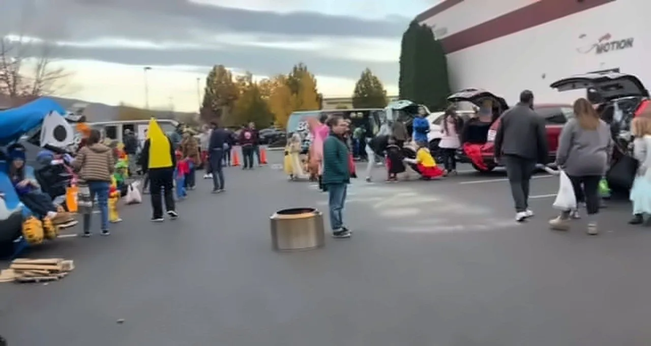 Families and kids in costumes trick-or-treating between decorated car trunks in the Bodies in Motion parking lot in Boise at the 2024 Trunk or Treat