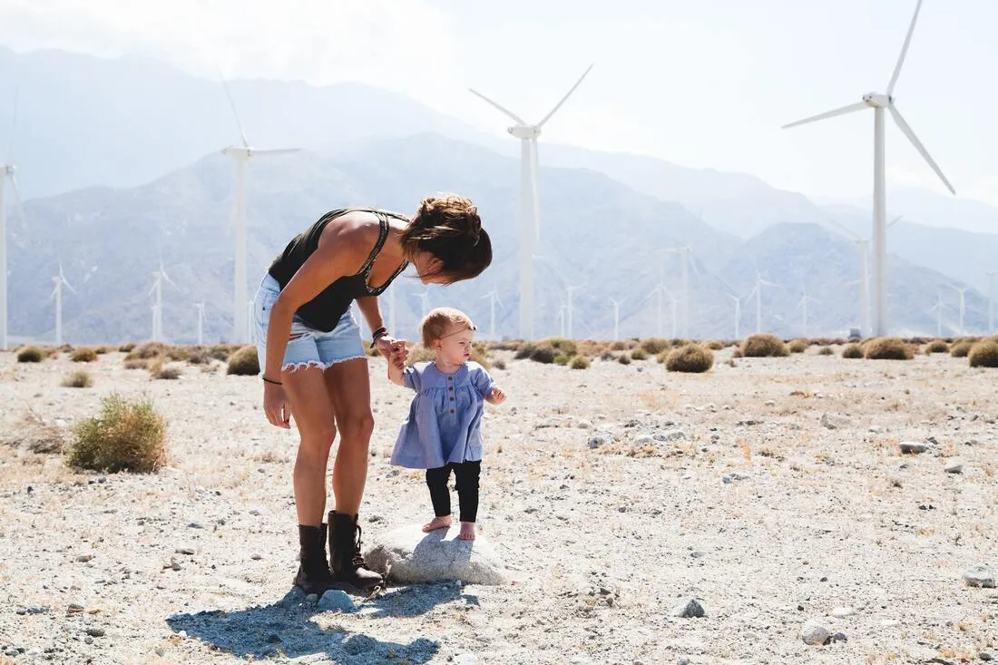 A parent holding a toddler's hand outdoors