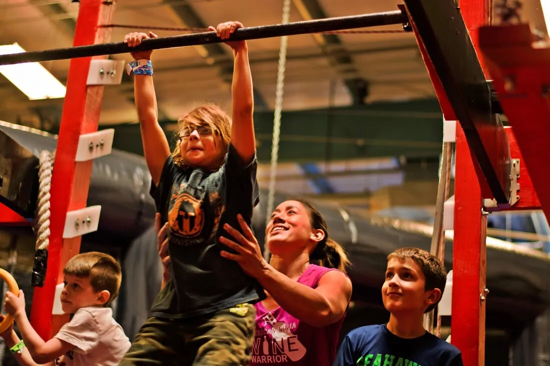 Campers cheering a friend hanging from a ninja warrior bar