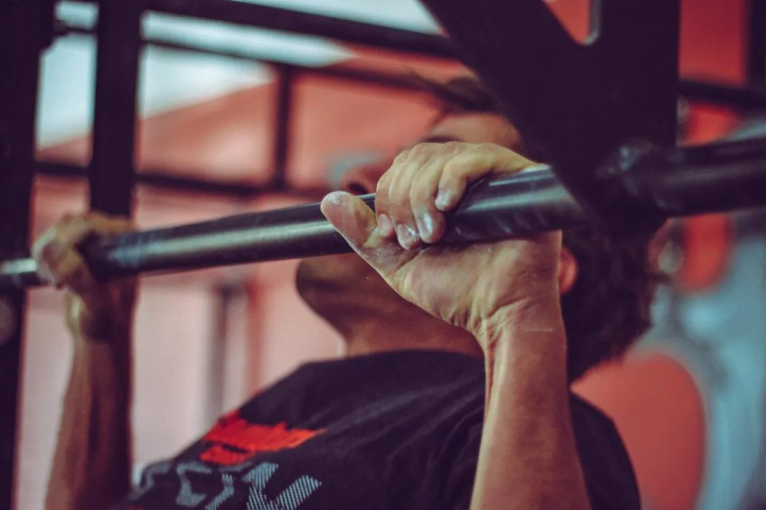 A close-up of a hand gripping a pull-up bar