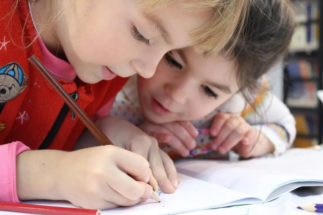 Two young children drawing together at a table