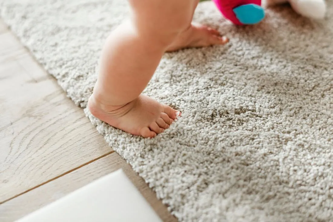 A toddler's bare feet standing on a soft rug